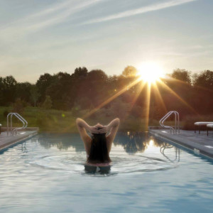 A guest enjoying a swim at sunset at Salamander Spa