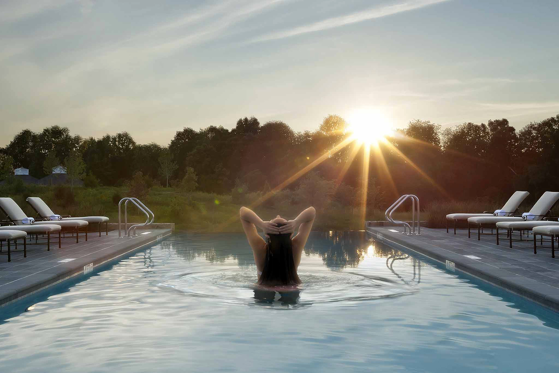 A guest enjoying a swim at sunset at Salamander Spa